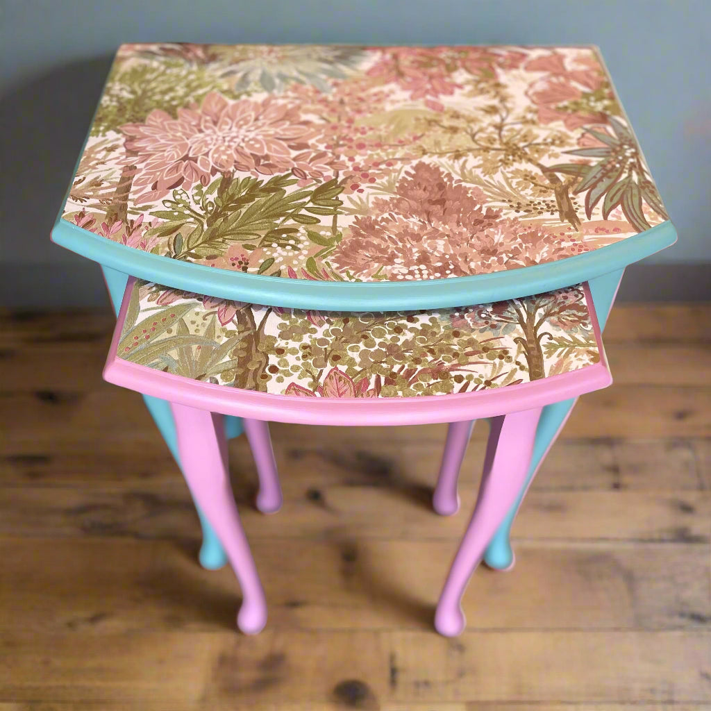 Set of two nesting tables with floral patterned tops on a wooden floor.