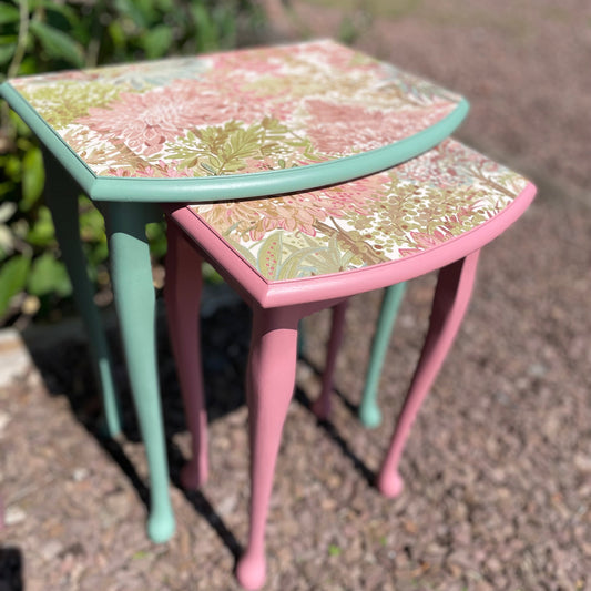 Two small, decorative tables with floral patterns on a textured surface.