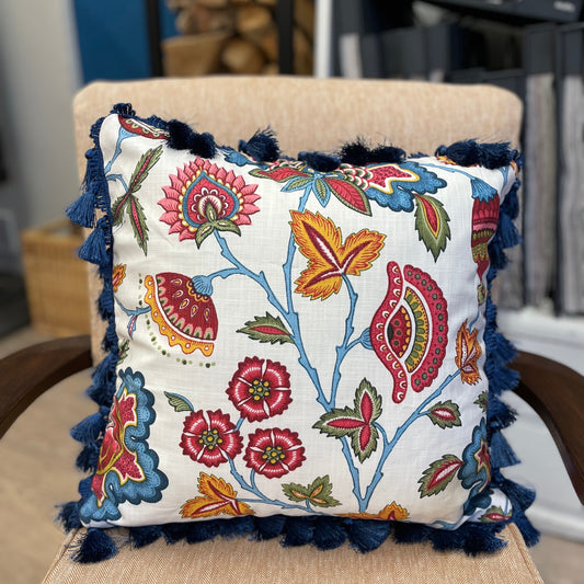 Decorative pillow with floral pattern and tassels on a chair
