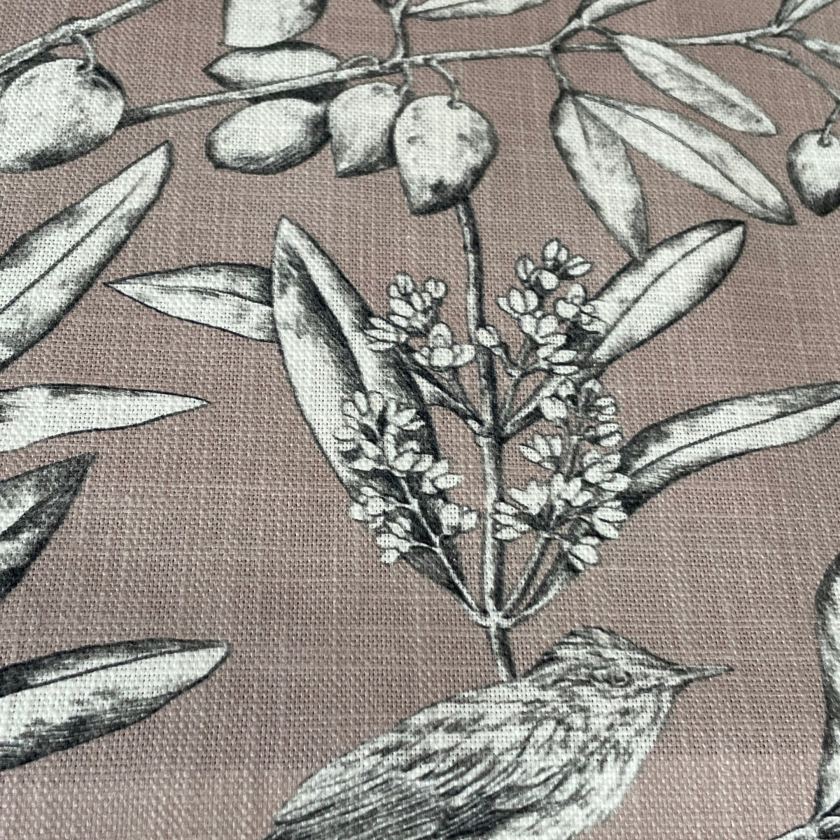 A close-up of a woven fabric with a botanical and bird print. The pattern features olive branches with leaves and olives in black and gray, set against a dusty mauve-pink background.